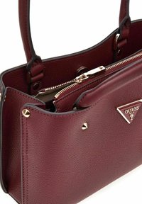 Bordeaux faux leren handtas met een gestructureerde vorm, gouden hardware, ritssluiting en decoratieve studs. Beschikt over dubbele handvatten.