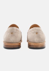 Scarpe in suede beige con tacco arrotondato, dotate di una soletta in pelle liscia e una suola in legno leggermente rialzata con un accento nero.