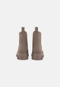 Brown ankle boots with elastic side panels and a thick, textured sole. Features pull tabs and a smooth surface.