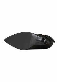 Stivale alla caviglia in suede nero con punta affusolata e dettagli in frange. La suola è elegante con una superficie in gomma nera testurizzata per una migliore aderenza.