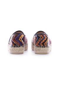 Espadrilles coloridos con un patrón en zigzag en púrpura, naranja y blanco, con una suela de yute trenzado y un ribete negro en la parte superior.