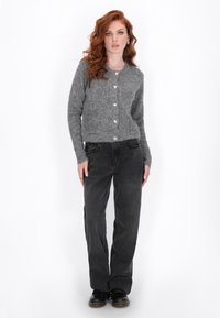 Cardigan tricotat gri cu guler rotund, decorat cu cinci butoane; asociat cu blugi negri, largi, și încălțăminte neagră.