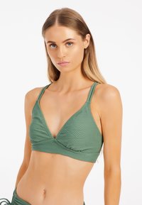 Žalias bikinio viršus su V formos iškirpte, su tekstūruotais geometrijos raštais, reguliuojamomis petnešomis ir lygiu audinio paviršiumi.