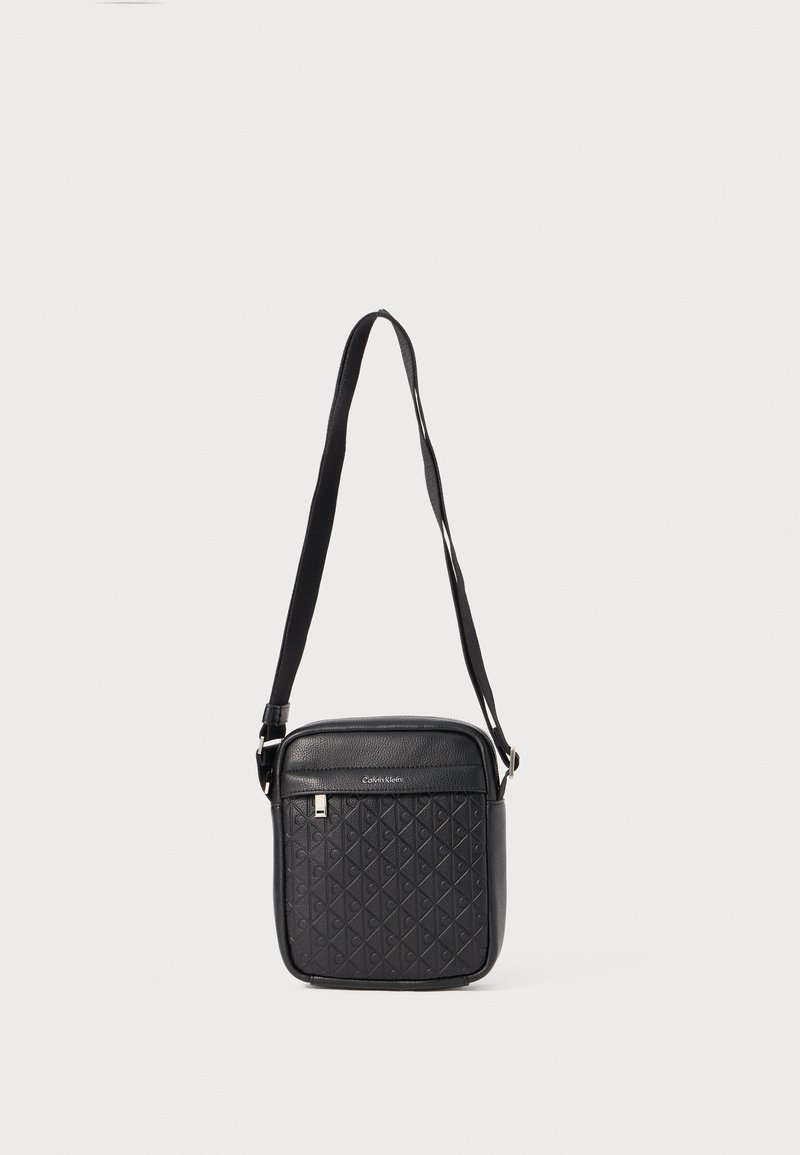Sac bandoulière noir avec un motif de diamant texturé, en cuir, dessus lisse, sangle ajustable et accents en métal argenté.