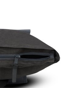 Mörkgrå tygpåse med dragkedjestängning. Har en slät yta och en klaffdesign med förstärkt kant och en webbad dragögla.