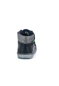 Bota para niño pequeño en negro y plata con un acabado brillante, correa de velcro y suela de goma texturizada. Costuras decorativas a lo largo de los bordes.