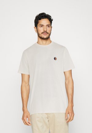 Heledad beez-shirt, lühikeste varrukatega, ümmarguse kaelusega, millel on vasakul rinnal väike mitmevärviline illustratsioon. Sile tekstuur.