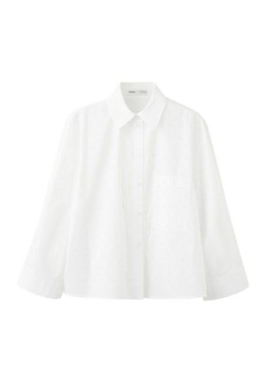Biała, długorękawowa koszula na guziki z subtelną kropkowaną fakturą, zakończona spiczastym kołnierzykiem i pojedynczą kieszenią na piersi, przedstawiona na białym tle.