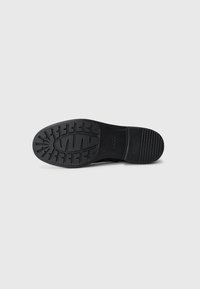 Black shoe sole with a textured tread pattern, featuring rubber material and a smooth finish, designed for traction and durability.