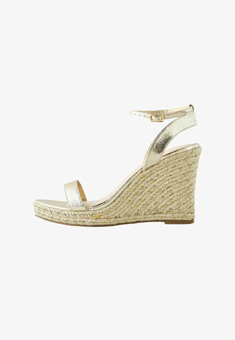Sandale compensée avec plateforme en jute tissée, bride de cheville dorée métallique et bout ouvert sur fond blanc.