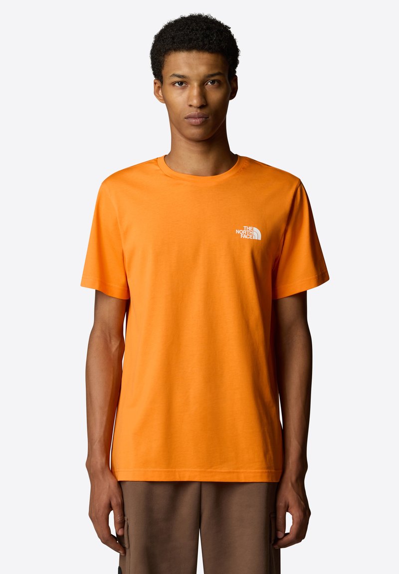 T-shirt di cotone arancione con maniche corte e collo rotondo. Presenta un logo bianco sul petto a sinistra. Tessuto morbido e vestibilità regolare.