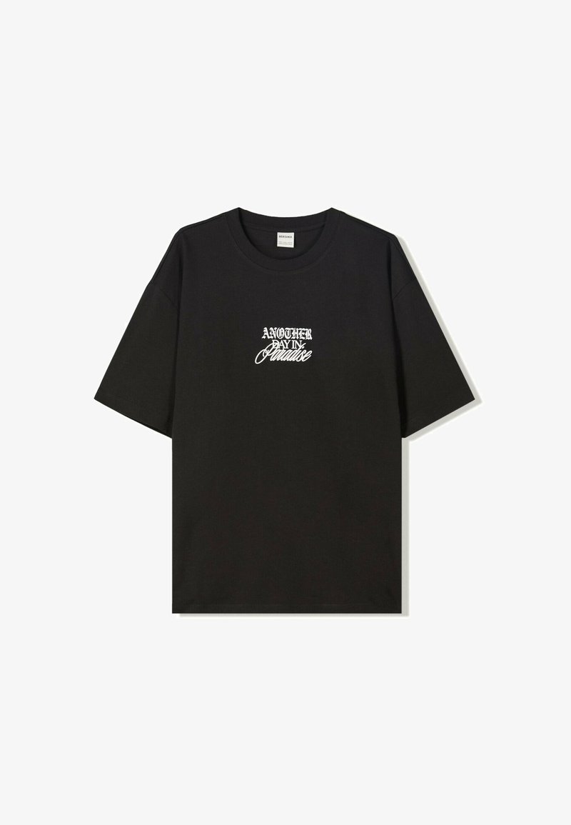 Svart bomull T-shirt med kort ärm som har vit stiliserad text "EN ANNAN DAG I PARADIS" på framsidan. Normal passform och rund hals.