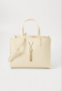 Beige faux leather handbag with dual handles and an adjustable shoulder strap. Features a gold-tone accent with a hanging tassel detail.