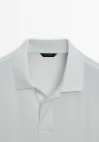 Polo bleu clair à manches courtes avec col côtelé et patte à deux boutons, posé à plat sur fond blanc.