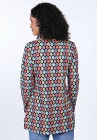 Langärmlige Tunika mit einem mehrfarbigen Blättermuster auf dunklem Hintergrund, mit Rundhalsausschnitt und abgerundetem Saum. Aus weichem, leichtem Stoff.