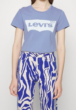 Person wearing a purple Levi's t-shirt and high-waisted pants with a blue and white abstract zebra print pattern.