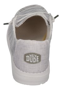 Scarpa slip-on grigia e bianca in tessuto con tomaia texturizzata, lacci elastici e suola in gomma bianca. Presenta una patch con il logo "HEY DUDE" sul tallone.