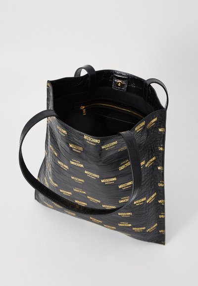 Geantă tote alcătuită din piele ecologică cu un model de crocodil negru și imprimare aurie cu logo-ul Moschino, având două mânere și un buzunar interior cu fermoar pentru depozitare în siguranță.