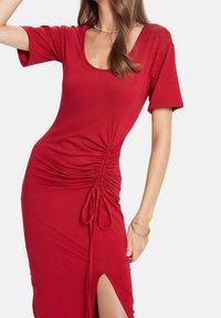 Rotes Jersey-Kleid mit kurzen Ärmeln, Rundhalsausschnitt, seitlichen Raffungselementen und verstellbarem Band am Saum für einen hohen Schlitz-Effekt.