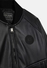 Czarna skórzana kurtka bomber o fakturowanym wykończeniu, z prążkowanym kołnierzem, zamkiem błyskawicznym na środku oraz okrągłą naszywką z literą "G".