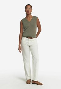 Olivgrön ärmlös V-ringad topp, i kombination med off-white raka byxor och bruna platta sandaler. Enkel design och lätt textur.