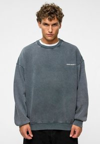 Grijze oversized sweatshirt met raglanmouwen en rib gebreide manchetten. Bevat logo-tekst op de linkerkant van de borst. Gestructureerde stof met een versleten uitstraling.