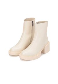 Bottes de cheville blanches en simili cuir avec un talon bloc, présentant une fermeture éclair sur le côté et un design sans couture, une texture lisse et un bout rond.