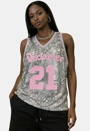 Donna che indossa un top da basket in paillettes argento con rifiniture rosa, testo "Disclaimer" e numero 21 in rosa, abbinato a pantaloni neri.