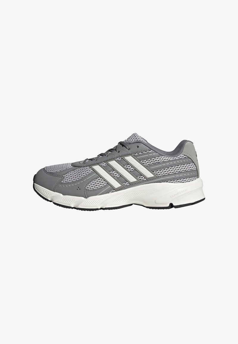 Chaussure de course athlétique grise et blanche avec tige en mesh, bandes blanches sur les côtés, semelle coussinée et fermeture à lacets.