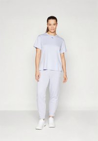 helelillast spordiriiete komplekt, mis koosneb lühikeste varrukatega topist ja kitsenevatest pükstest. Valmistatud pehmest materjalist, lihtsa disainiga ja ilma nähtavate mustriteta.