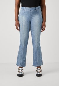 Svetlo modri flared jeans z visokim pasom in dvema sprednjima žepoma. Tkanina ima mehak občutek in subtilno zbledenje.