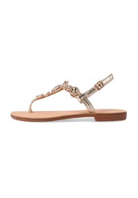 Sandalo piatto oro e beige con cinturini decorativi di perline e una cinghia alla caviglia con fibbia. Suola liscia, design open-toe e decorazioni a motivo.