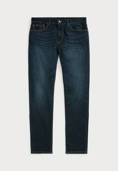 Jeans in denim blu scuro con taglio dritto, cinque tasche e cuciture color rame lungo le cuciture e le tasche. Senza segni di usura visibili.