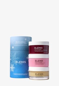 Ensemble de trois baumes nettoyants dans des pots; les couleurs incluent bourgogne, rose et or. Emballé dans une boîte cylindrique bleue avec un motif de flocon de neige.