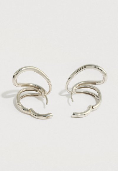 Ζευγάρι γυαλιστερών ασημένιων στριφτών κρίκων σκουλαρικιών με κούμπωμα ασφαλείας, σε λευκό φόντο.