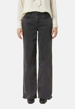 Jeans neri in denim a gamba larga con vita alta, quattro tasche e un lavaggio leggermente sbiadito. Abbinati a un top a maniche lunghe di colore chiaro.