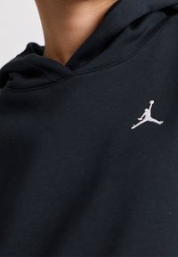 Sudadera con capucha negra hecha de material suave con un bolsillo tipo canguro y capucha con cordón. Cuenta con el logo Jumpman blanco en el pecho.