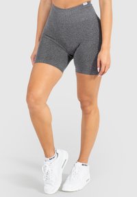 Shorts de vélo gris taille haute en tissu doux et extensible ; dotés d'une texture lisse et d'un design ajusté. Associés à des baskets blanches.