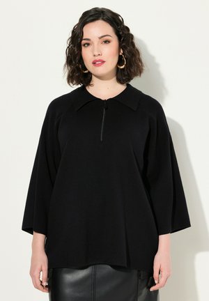 Pull noir à col avec fermeture éclair courte. Présente des manches amples et un tissu tricoté texturé.