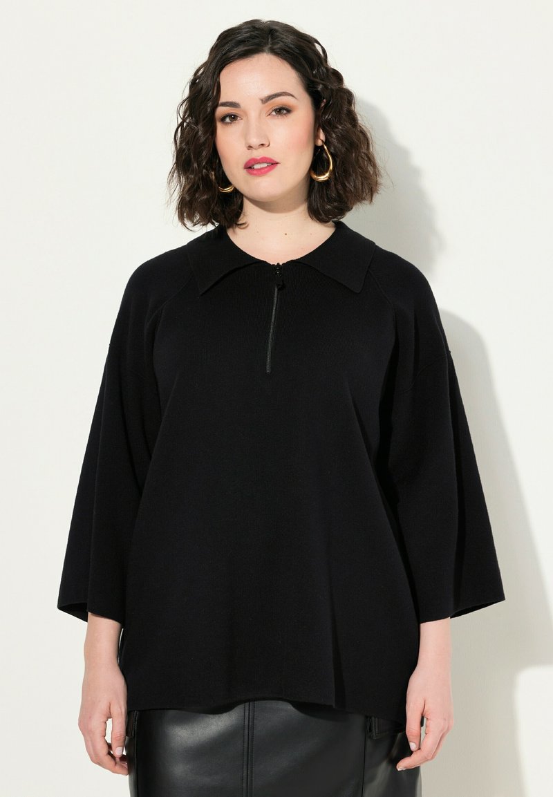 Maglione nero con colletto e chiusura a zip corta. presenta maniche ampie e un tessuto lavorato a maglia.