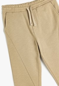 Beige joggingbroek met een elastische tailleband, trekkoord en zijzakken. Gemaakt van een zachte, textuurstof met een tapers ontwerp.
