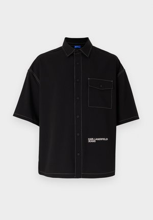 Black short-sleeve shirt made from smooth fabric, featuring white stitching, a front pocket, and a logo print on the lower side.