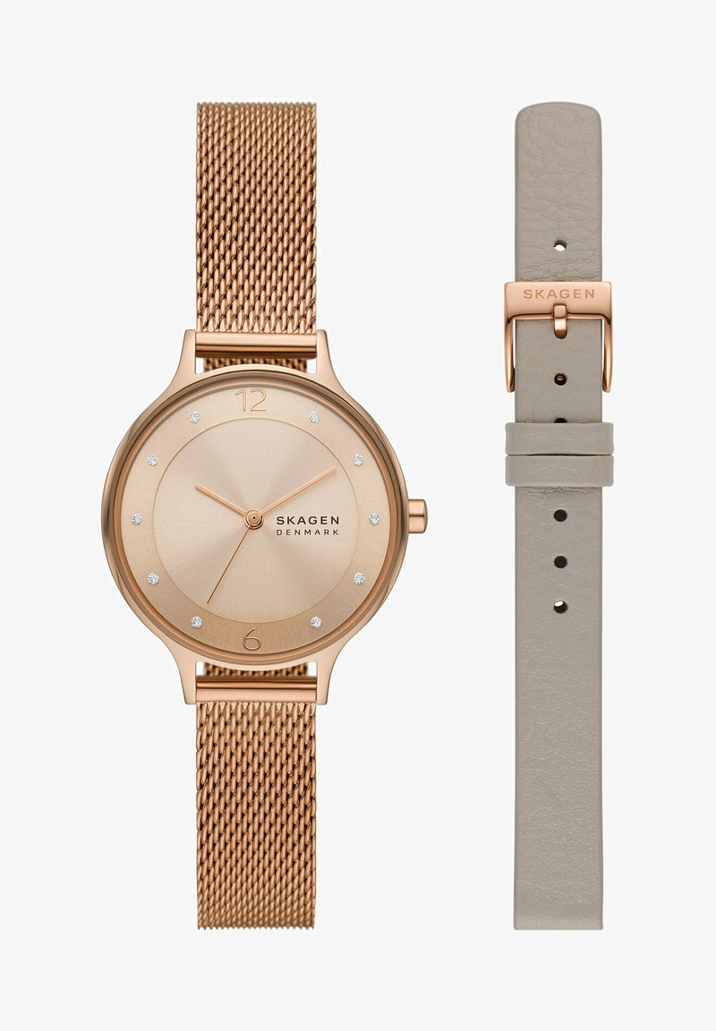 Montre Skagen en or rose avec bracelet en maille, cadran minimaliste avec index en cristal, et un bracelet en cuir beige supplémentaire avec boucle en or rose.