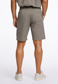Grå texturerade shorts med elastisk midja, med en bakficka och en avslappnad passform. Kombinerat med ljusa sneakers.