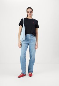 Melnas t-krekls ar mazu sarkanu sirds detaļu, gaiši zila plecu soma, zilas džinsu bikses un sarkanas plakanas kurpes. Vienkāršs dizains un neformīga piegriezuma.