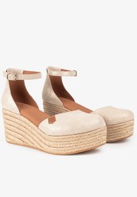 Chaussures à talons compensés en paillettes beiges avec plateforme en jute tressé, bride de cheville et design à bout rond. Texture lisse avec un talon élevé et robuste.