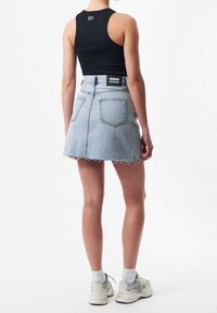 Denimhame, jossa on rosoinen helma, vaaleansininen väri, kaksi takataskua ja musta etiketti vyötäröllä. Yhdistetty mustan hihattoman topin kanssa.