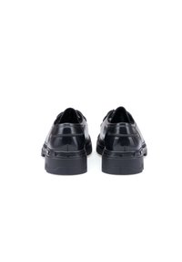 Ein Paar schwarze, polierte Lederschuhe mit dicken Gummisohlen, von hinten auf einem weißen Hintergrund gezeigt.