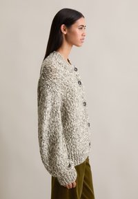 Cárdigan de punto en una suave mezcla de gris moteado y crema, con un cuello redondo, mangas oversized y botones negros.