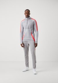Grijs sportieve trainingspak met hoge kraag en rozenkwarts accenten, gemaakt van rekbaar materiaal. Inclusief taps toelopende broek en een gestructureerd bovenpaneel.